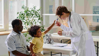 A healthcare professional treating a child patient sitting on their parent's lap