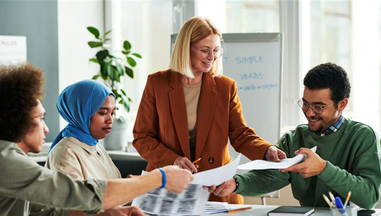 Three people sat round a desk exchanging papers