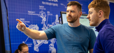 Two people looking and point at a screen in an engineering room