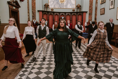 Students in Victorian clothing dancing in hall