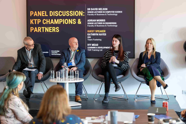Speakers on a panel talking to a crowd