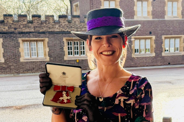 Woman smiling and holding an MBE medal