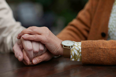 Two older people holding hands