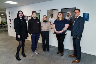Academics and students stood in front of photographs on the wall