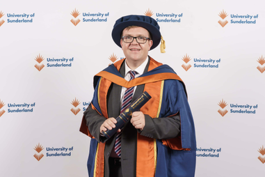 Man standing in robes and hat, holding a scroll
