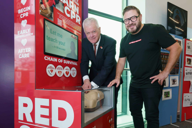 Two people next to a CPR simulator