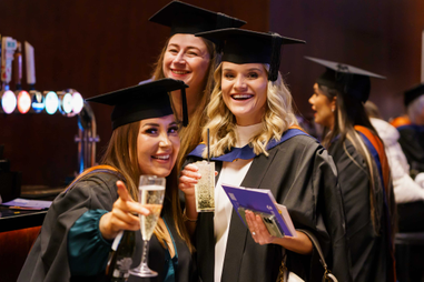 Three women in graduation gowns smiling