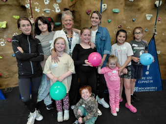 Adults and children standing at the bottom of a climbing wall