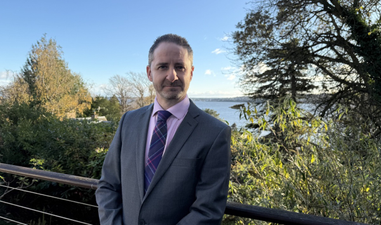 Graduate stood in front of trees