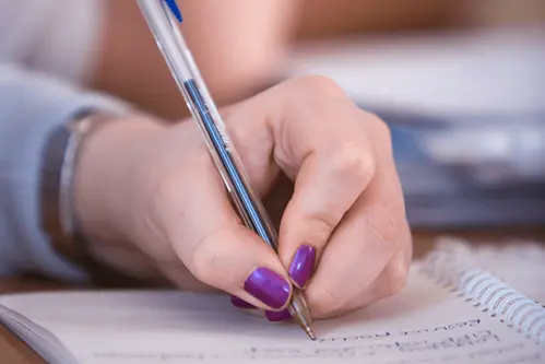 A close up of a persons hand writing on a notepad