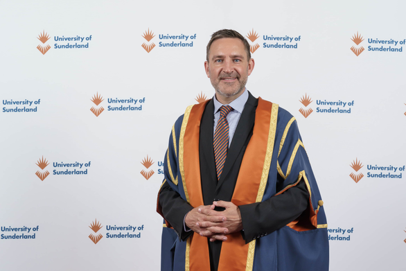 Man standing in graduation ceremony robes