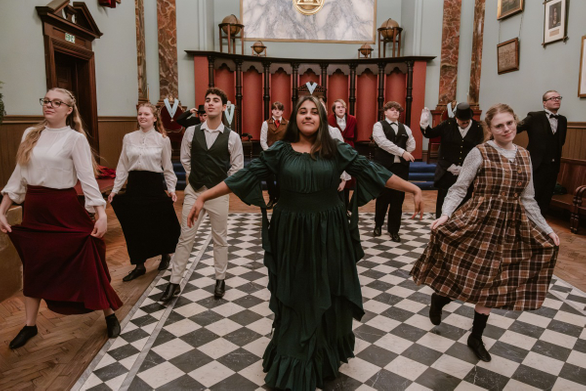 Students in Victorian clothing dancing in hall