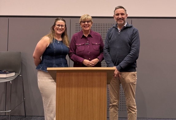 Three people standing at a podium