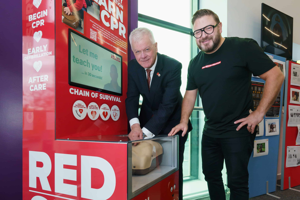 Two people next to a CPR simulator