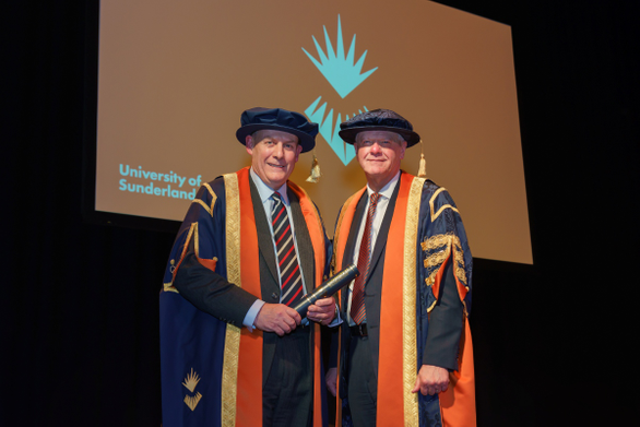 Vice-chancellor and charity trustee chair stood on stage in ceremonial robes