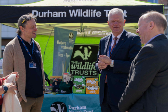 University staff at market stall with volunteer