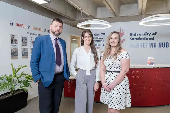 Three graduates standing inside the University of Sunderland's Marketing Hub