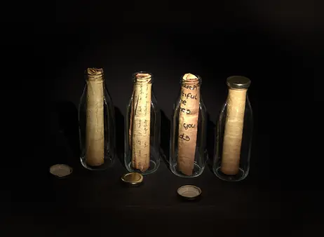 4 glass bottles with rolled up paper inside on a dark background