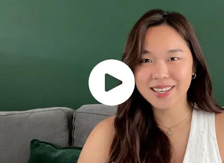 A student smiling facing the camera with a play button overlay