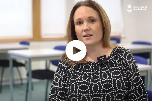The thumbnail for Enterprise and Innovation video. It is a member of staff being interviewed in a classroom with desks behind.