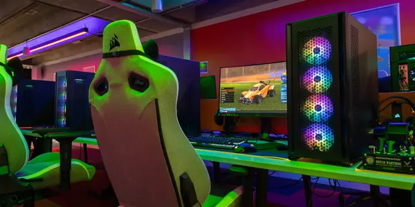 Gaming chair infront of a computer screen with games on it and dark, colourful lights