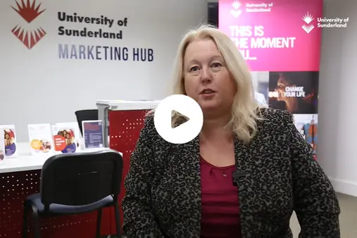 A thumbnail for a video on The Marketing Hub. It features a play button in the centre and a member of our academic staff talking with The Marketing Hub sign in the background