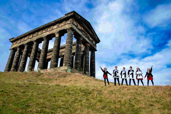 Children standing on hill beside a monument