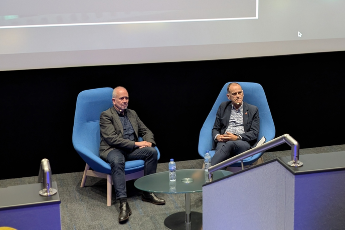Speakers sat on chairs talking to crowd