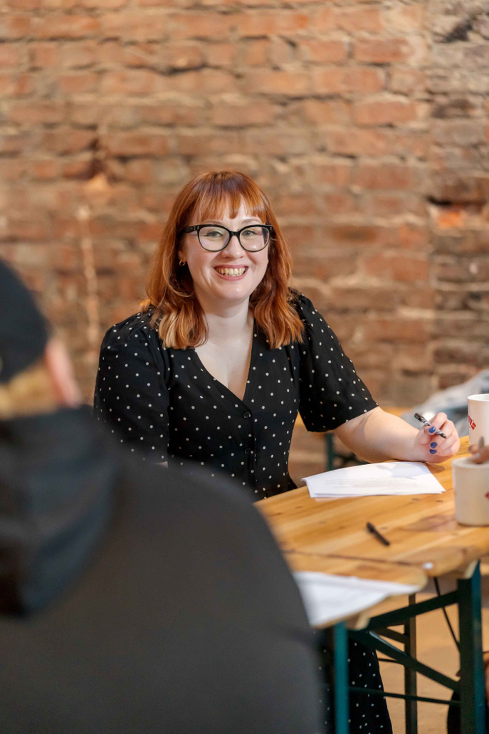 Dr Becky Allen sitting around a table with musicians at the AI in Music event at Pop Recs in Sunderland