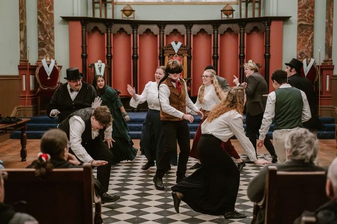 Students in Victorian clothing dancing in hall