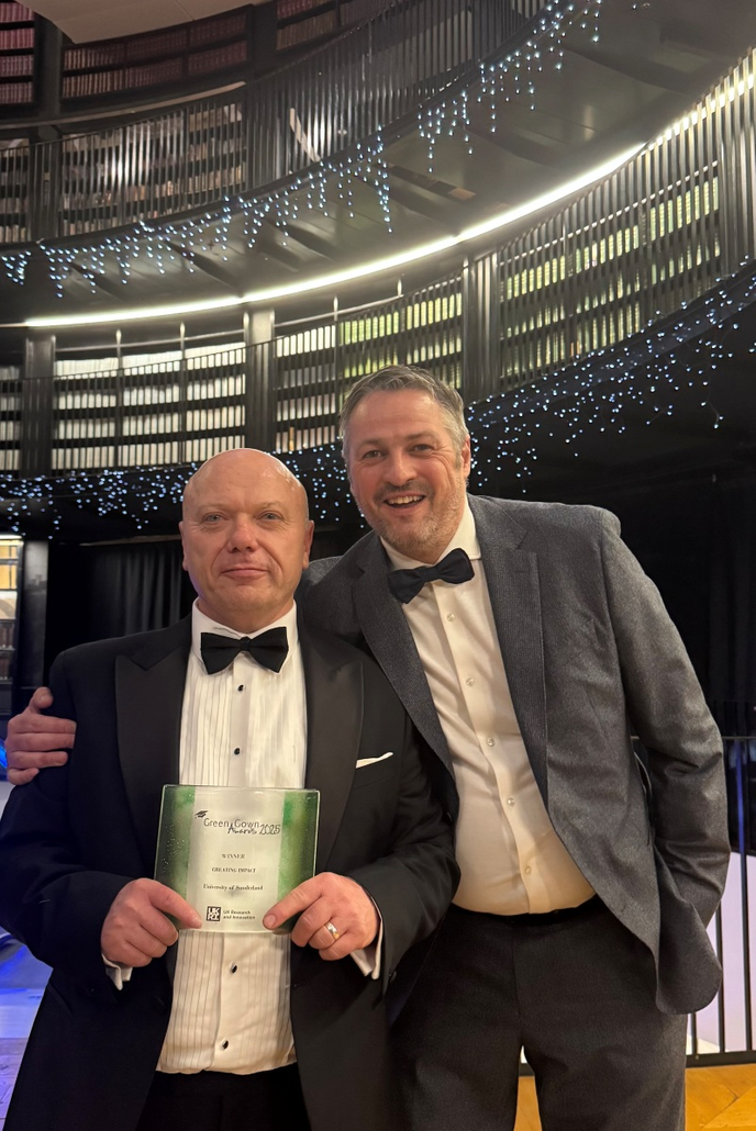 University staff stood together with award