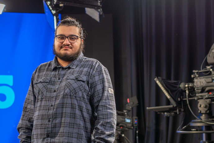 Student standing beside camera equipment