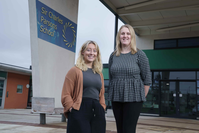 Two women standing outside of a school
