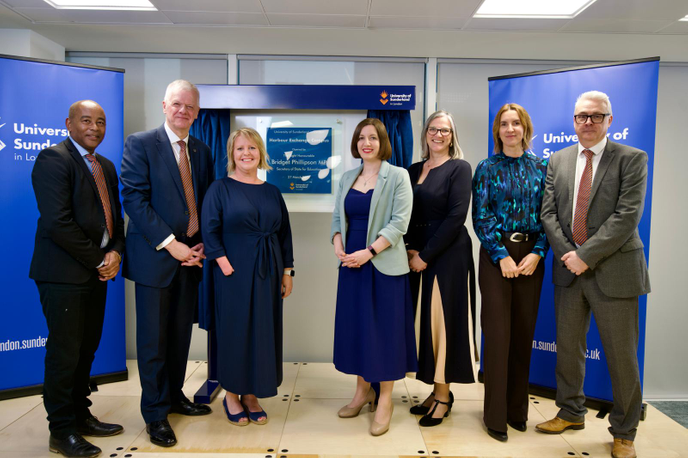 Staff and guests stood together around a plaque