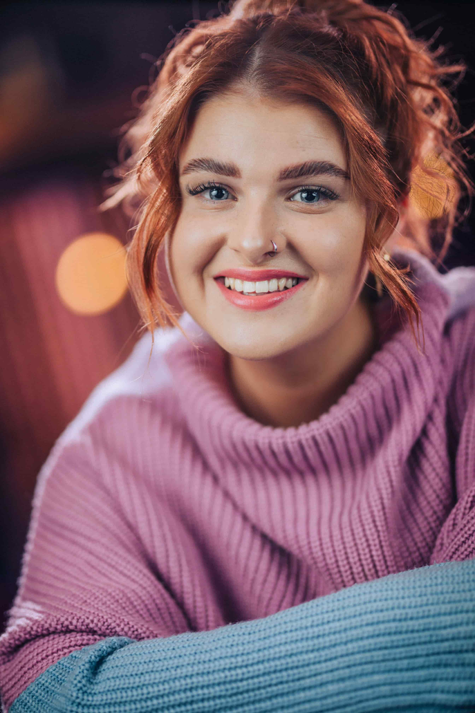 Professional headshot of Katie Stubbs wearing a pink jumper