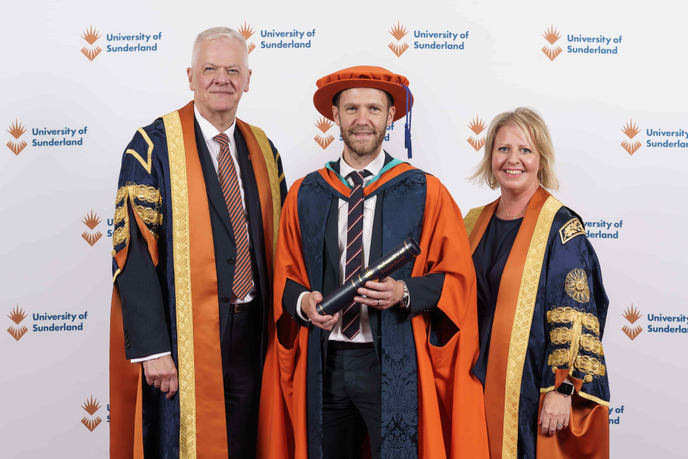 Three people standing in graduation robes
