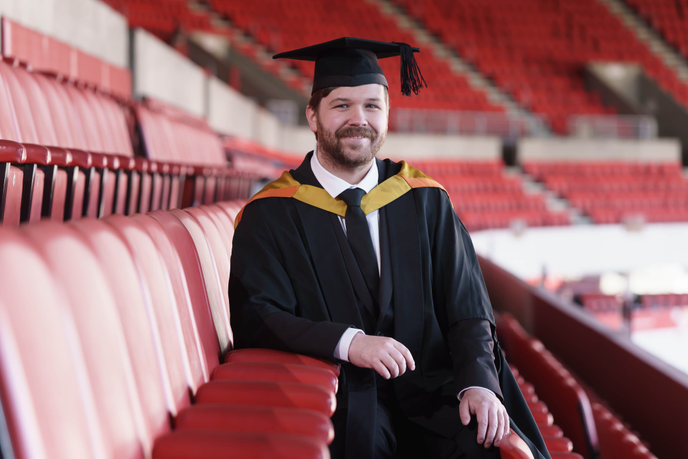 Graduate sitting in a football stadium