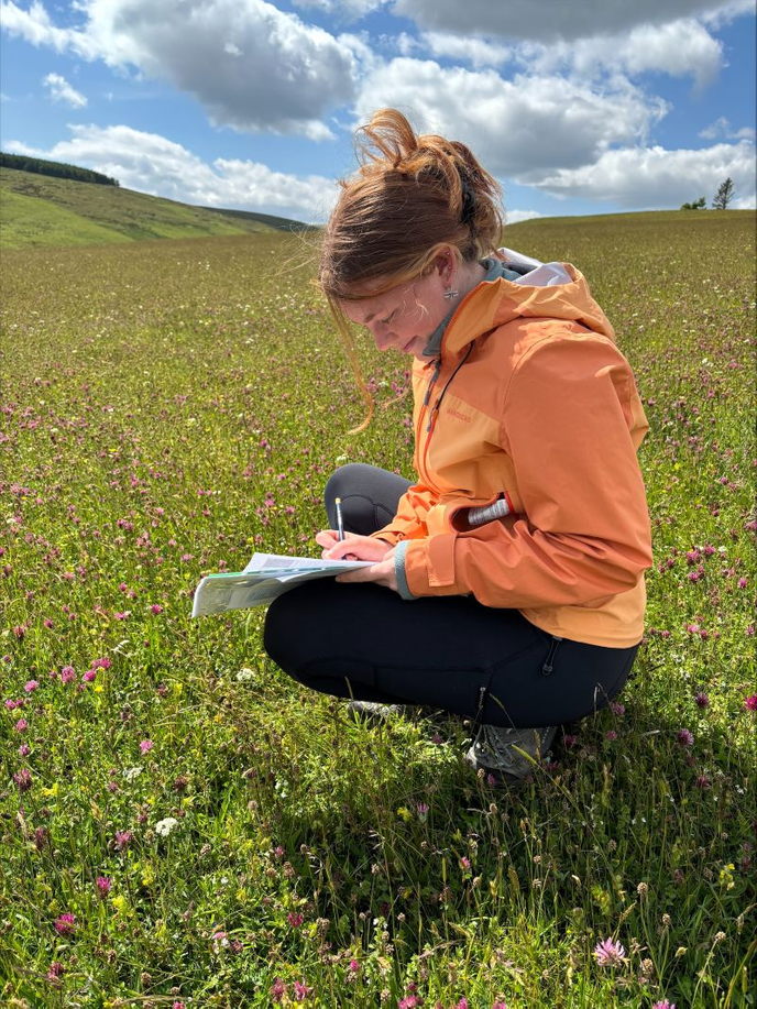 Graduate kneeling in a meadow
