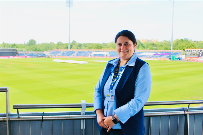 Woman standing infront of cricket pitch