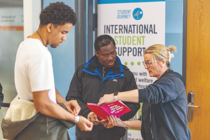 University of Sunderland staff member showing student a booklet