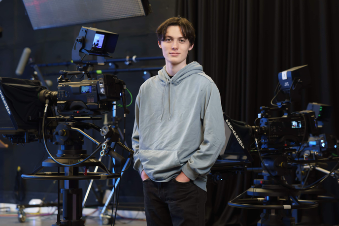Student standing beside camera equipment