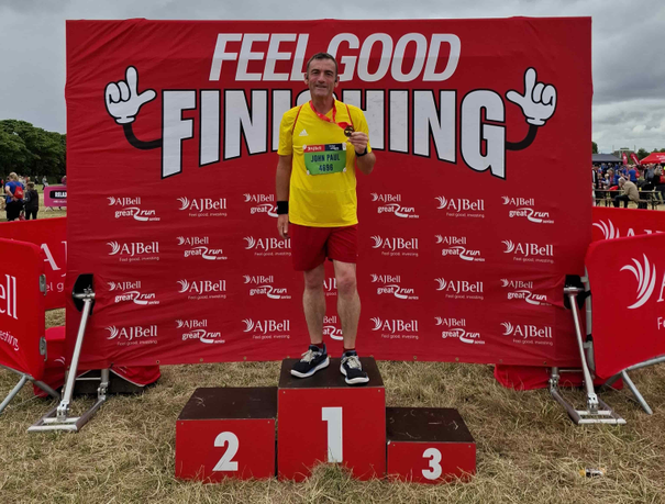 Man standing holding a medal