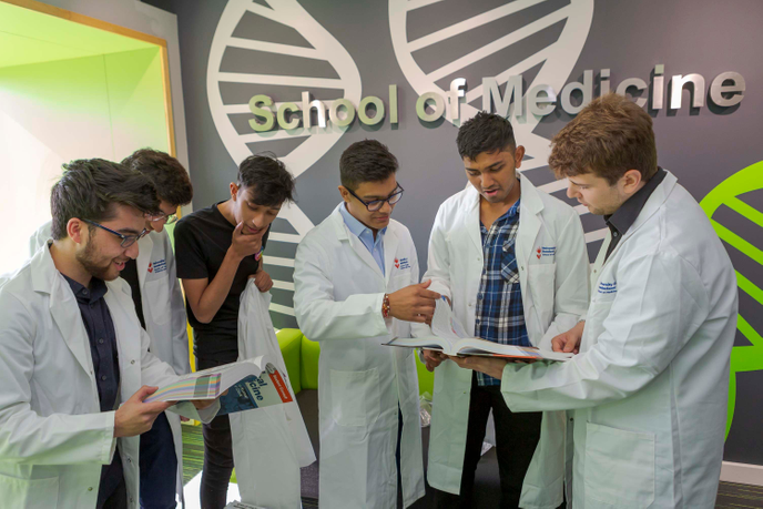 A group of students in white overalls at the University of Sunderland's School of Medicine