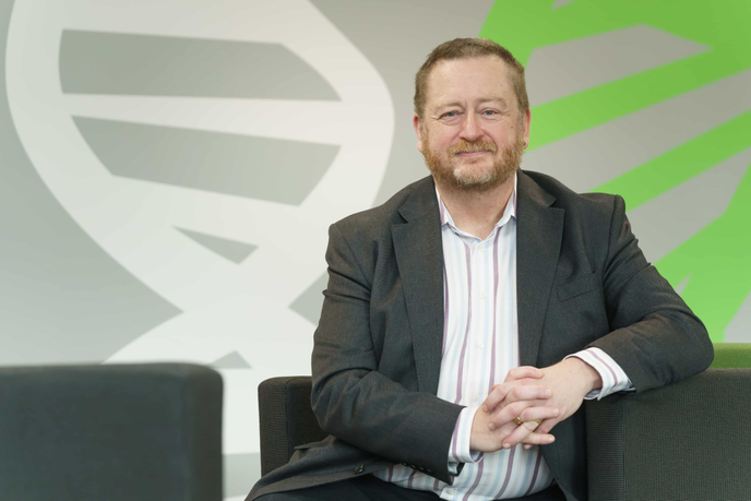 Dr Jon Rees sitting infront of colourful wall