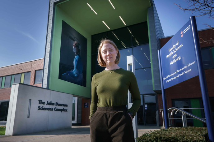Academic stood in front of university building with giant print on it
