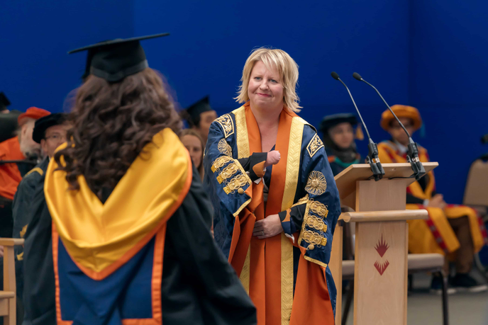 University Chancellor on graduation stage with student