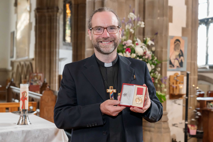 Reverend Chris Howson standing with his British Empire Medal