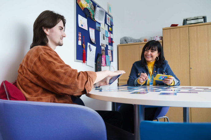 Staff member and student using cards while talking
