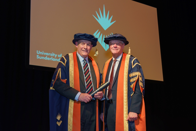 Vice-chancellor and charity trustee chair stood on stage in ceremonial robes