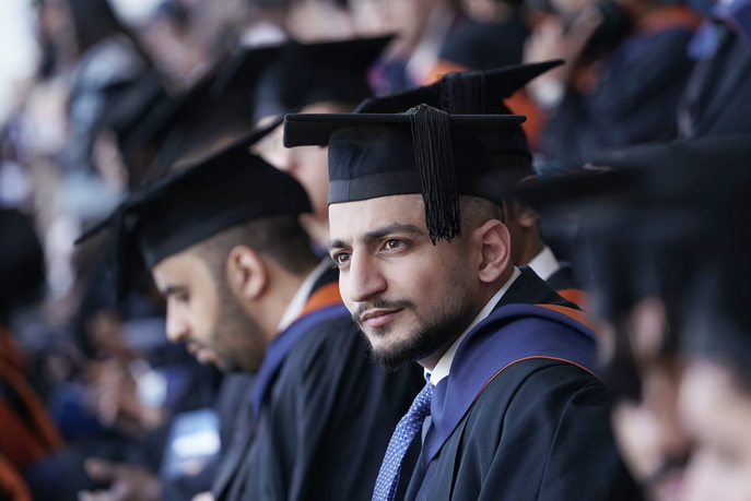 Student sitting in his cap and gown at the University of Sunderland's graduation ceremony at the Stadium of Light